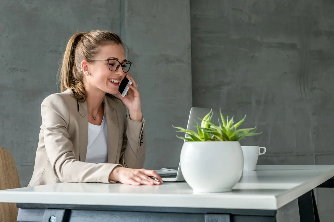A young woman on the phone and working on her laptop as a team assistant